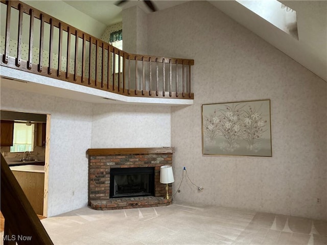 312 Chesapeake Cv, Painesville, OH 44077 - unfurnished living room with a brick fireplace, carpet, high vaulted ceiling, and wallpapered walls