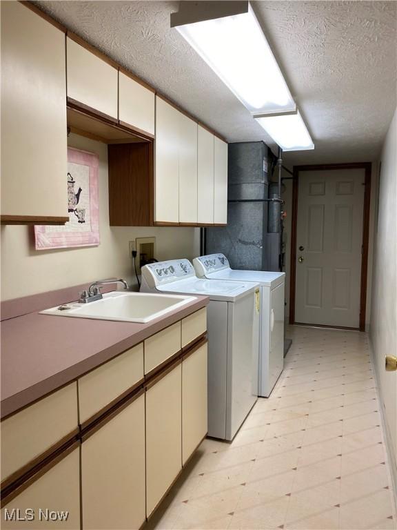 312 Chesapeake Cv, Painesville, OH 44077 - clothes washing area with cabinet space, washer and dryer, a textured ceiling, and light floors