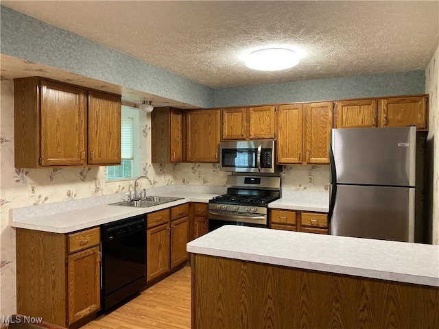 312 Chesapeake Cv, Painesville, OH 44077 - kitchen with appliances with stainless steel finishes, a sink, brown cabinetry, a textured ceiling, and light countertops