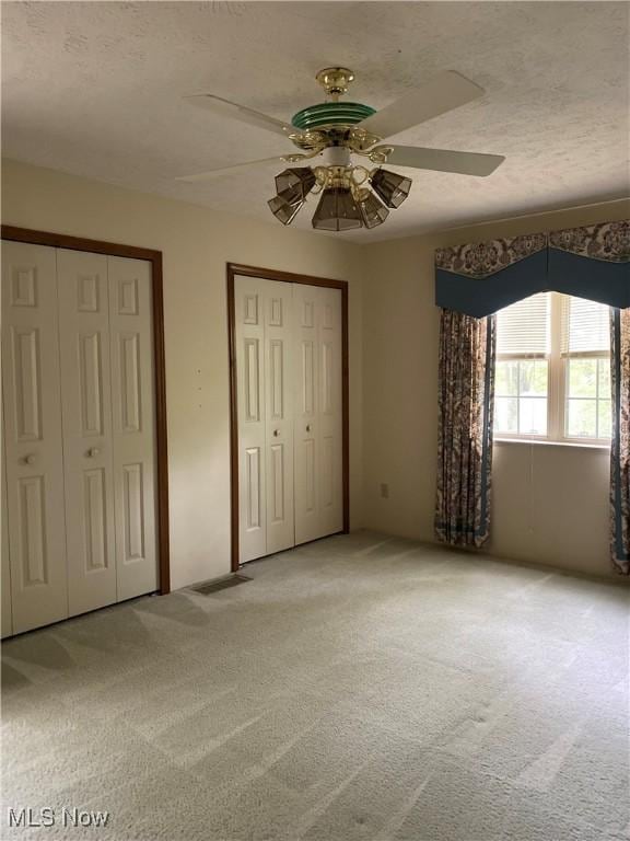 312 Chesapeake Cv, Painesville, OH 44077 - unfurnished bedroom featuring light colored carpet, two closets, a ceiling fan, and a textured ceiling