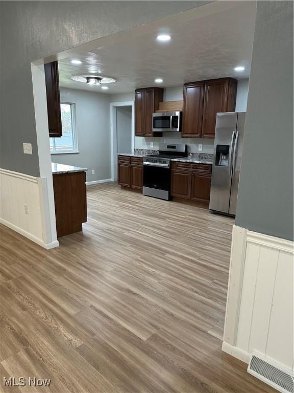 133 Bass Dr, Weirton, WV 26062 - kitchen featuring dark brown cabinetry, visible vents, appliances with stainless steel finishes, light wood-type flooring, and a wainscoted wall
