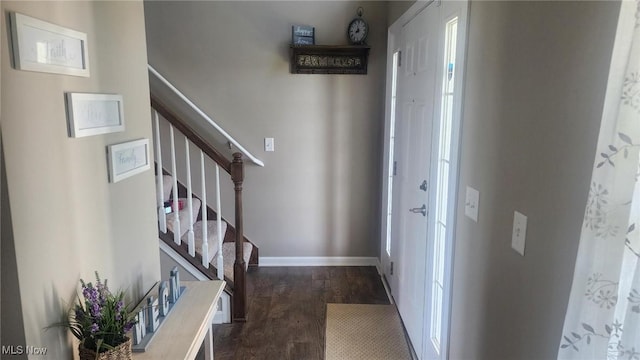 foyer entrance featuring dark wood-style floors, stairs, and baseboards