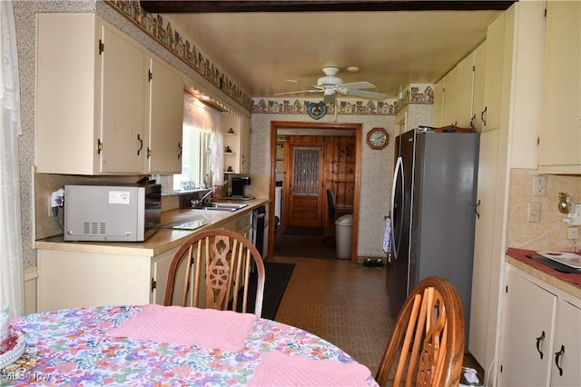 kitchen featuring a sink, freestanding refrigerator, a ceiling fan, wallpapered walls, and white microwave