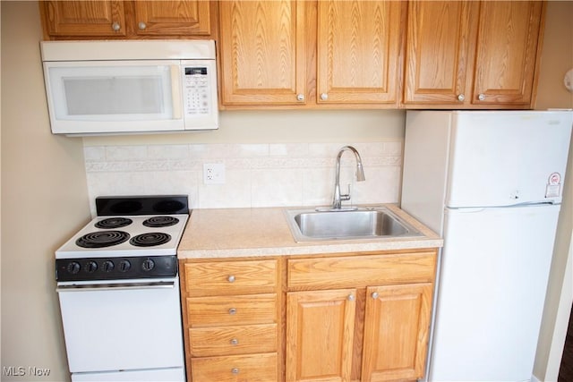 kitchen featuring white appliances, decorative backsplash, a sink, and light countertops