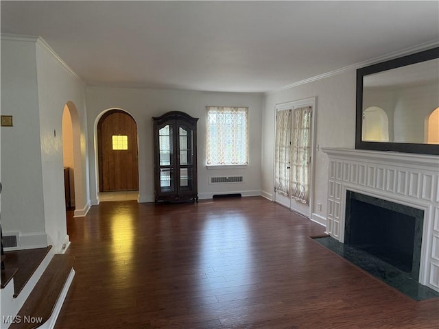 unfurnished living room with arched walkways, ornamental molding, and dark wood-style flooring