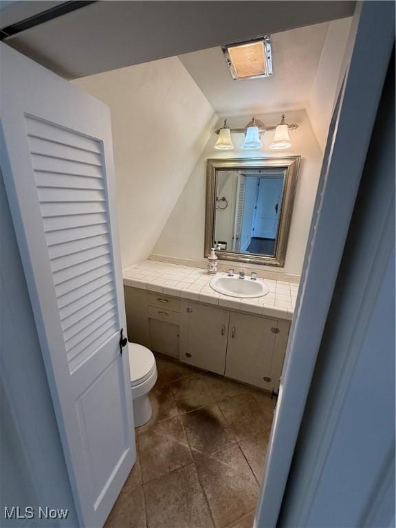 bathroom with vanity, vaulted ceiling, and toilet