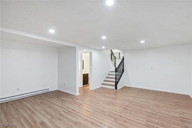 finished below grade area with stairs, recessed lighting, light wood-type flooring, and a baseboard radiator