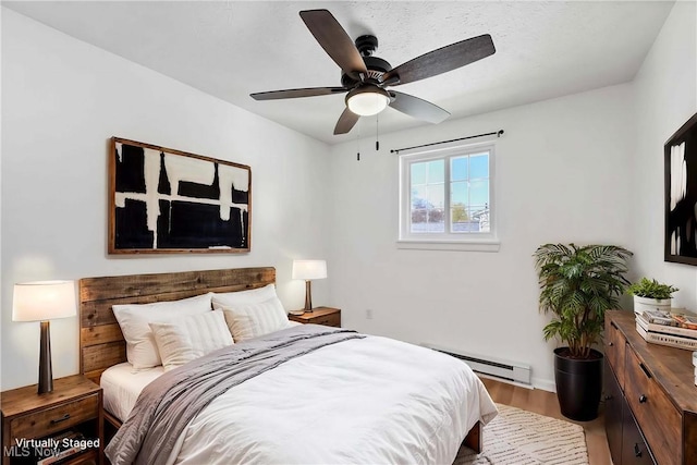 bedroom with a ceiling fan, baseboard heating, and wood finished floors