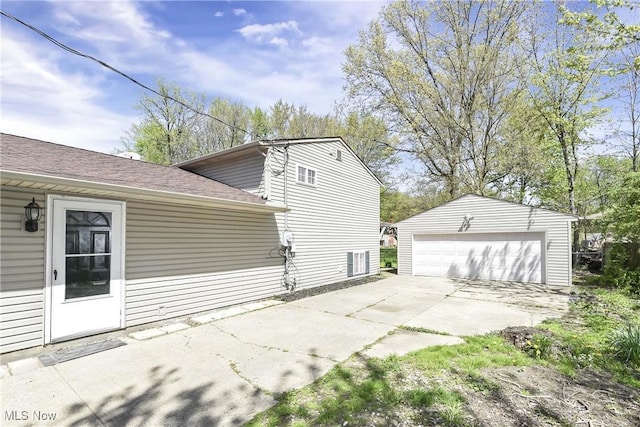view of side of home with a detached garage, an outdoor structure, and roof with shingles