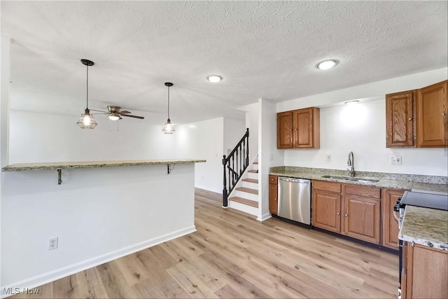 kitchen featuring light wood-style floors, ceiling fan, brown cabinets, a sink, and appliances with stainless steel finishes