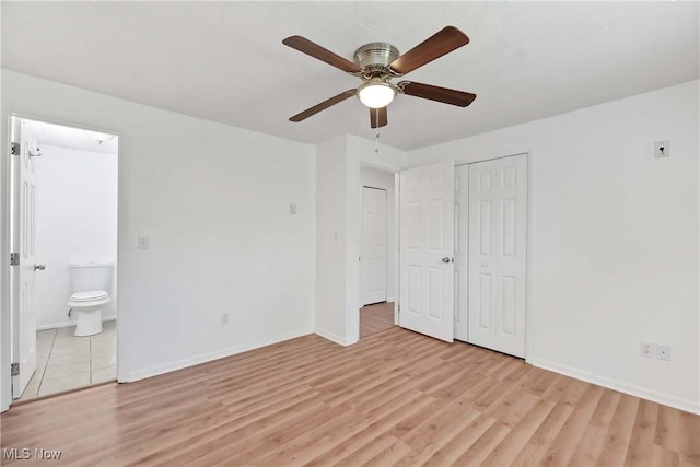 unfurnished bedroom with light wood-style floors, baseboards, and ensuite bathroom