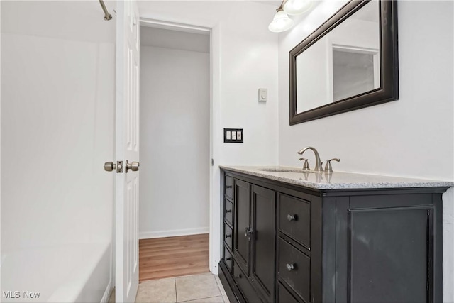 full bath with a bathing tub, tile patterned floors, baseboards, and vanity
