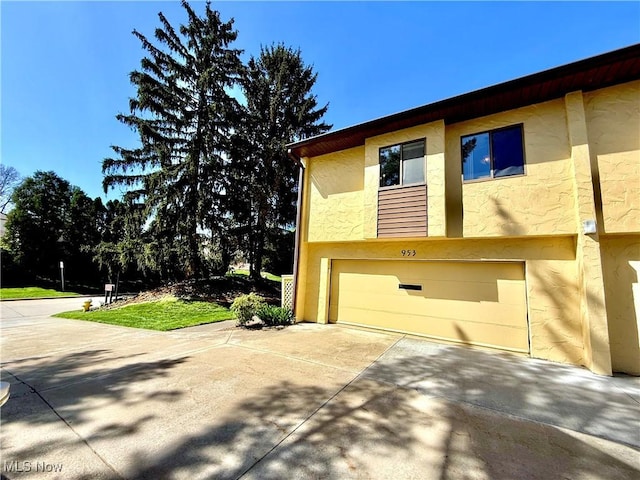 view of side of home with an attached garage, stucco siding, and concrete driveway
