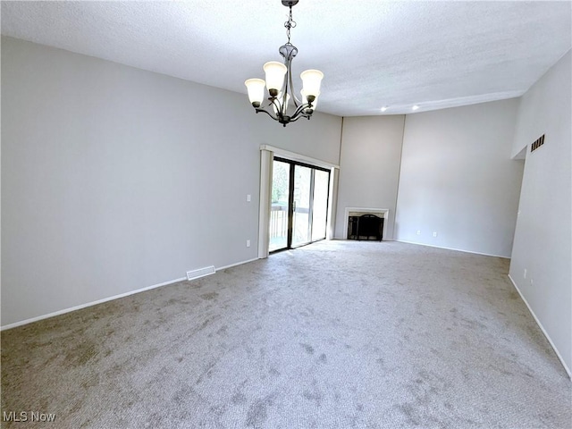 unfurnished living room featuring carpet floors, a textured ceiling, a chandelier, and visible vents