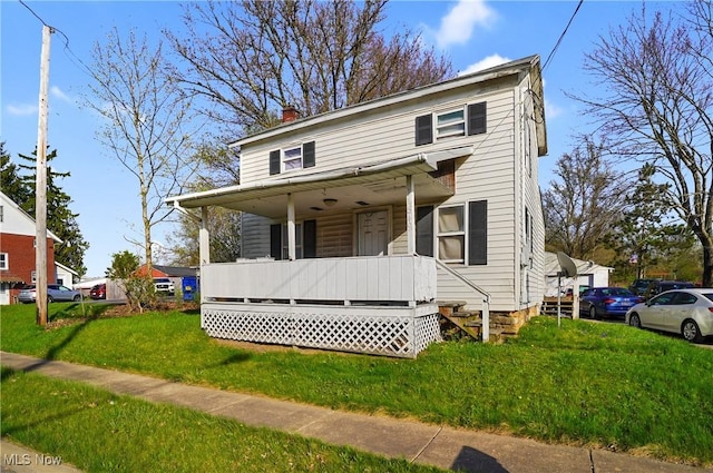 view of front of property featuring a chimney, a porch, and a front lawn