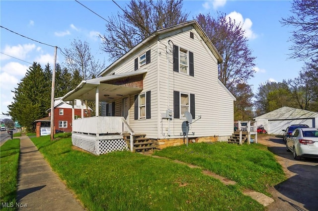 view of side of property featuring a yard, covered porch, and a detached garage