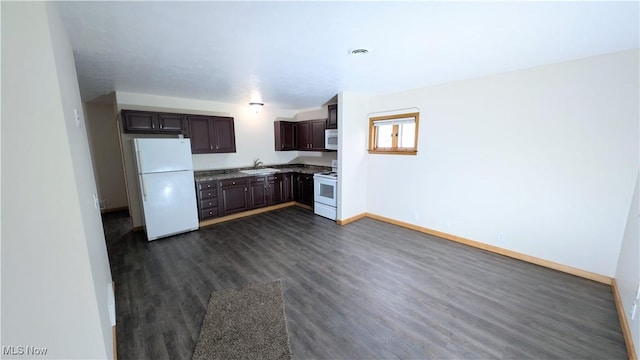 kitchen with dark brown cabinetry, a sink, baseboards, white appliances, and dark wood-type flooring