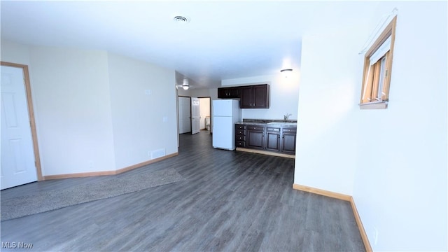 unfurnished living room with baseboards, visible vents, and dark wood-type flooring