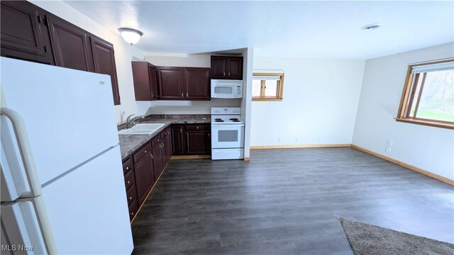 kitchen featuring dark brown cabinets, white appliances, baseboards, dark wood-style floors, and a sink