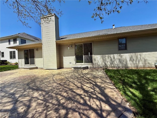 rear view of property featuring a patio and a chimney