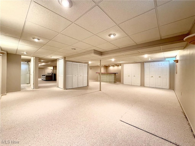 finished below grade area with carpet floors, baseboards, and a drop ceiling