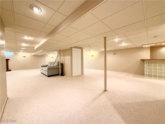 finished basement with carpet, baseboards, a bar, and a paneled ceiling