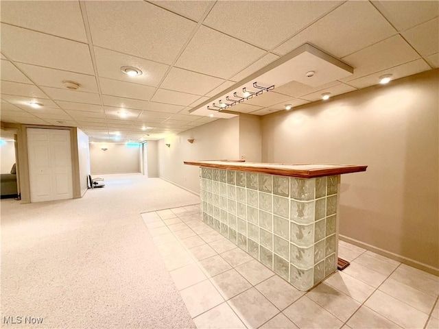 bar featuring baseboards, a dry bar, light tile patterned flooring, and a paneled ceiling