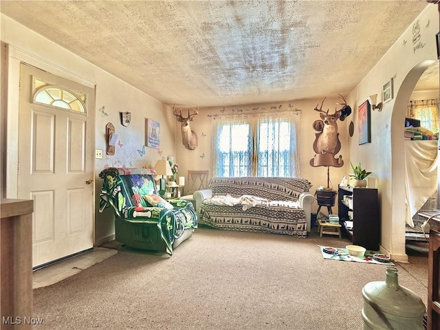 living area featuring arched walkways, a textured ceiling, and carpet flooring