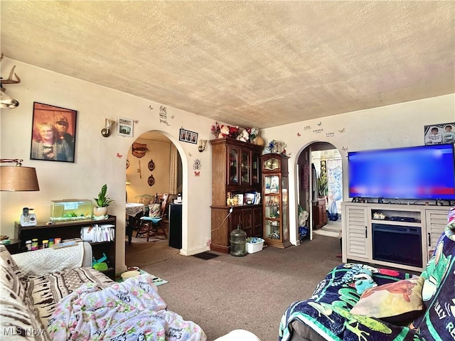 carpeted living area featuring arched walkways and a textured ceiling