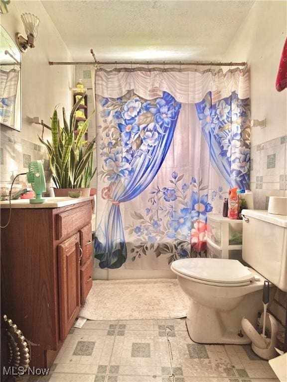 full bath with toilet, a textured ceiling, shower / tub combo with curtain, and vanity