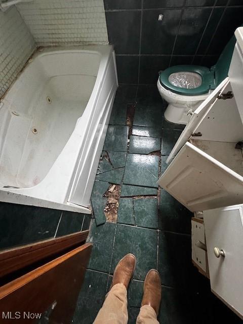 full bathroom with tile walls, tile patterned flooring, toilet, and a bathtub