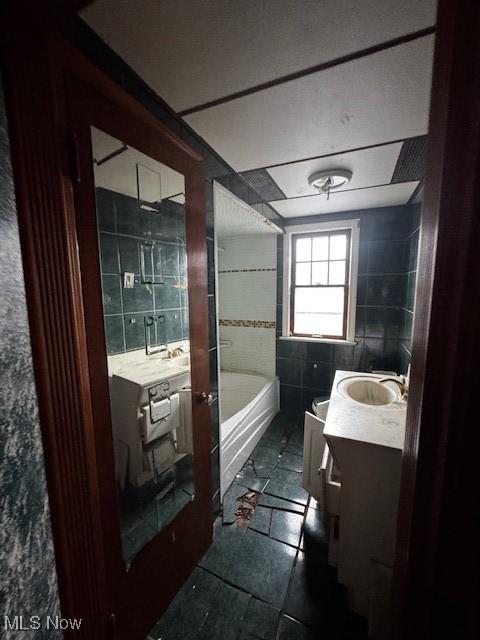 full bathroom with vanity, a bathing tub, tile patterned floors, and tile walls