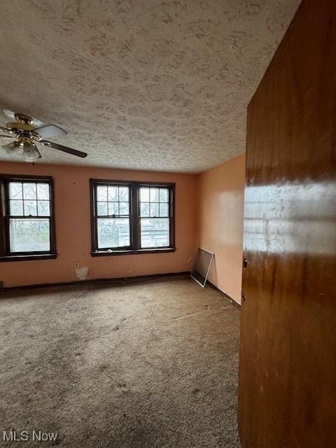 carpeted empty room with a ceiling fan, a textured ceiling, and a healthy amount of sunlight