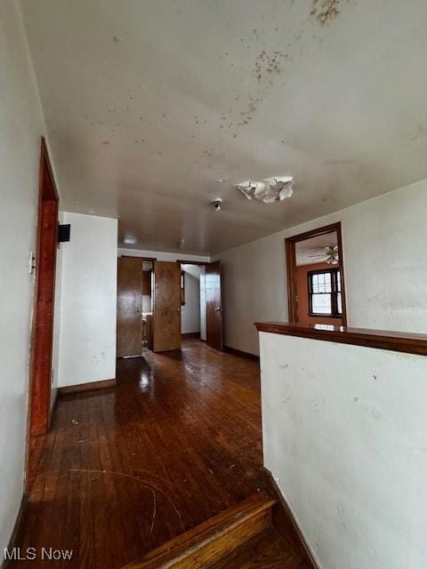 unfurnished room with baseboards and dark wood-style floors