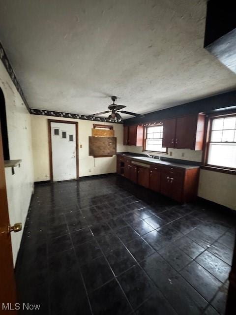 kitchen with a ceiling fan, dark countertops, a sink, and dark tile patterned floors