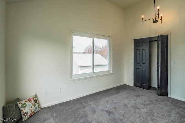 unfurnished bedroom featuring baseboards, carpet flooring, and a notable chandelier