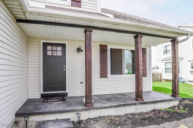 entrance to property with a porch and a shingled roof