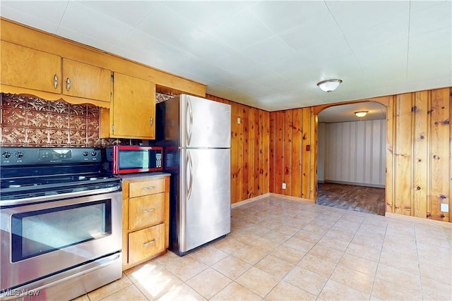441 4th St, Bergholz, OH 43908 - kitchen featuring stainless steel appliances, arched walkways, wood walls, and brown cabinetry
