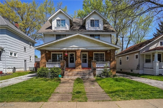 american foursquare style home featuring covered porch, brick siding, and a front yard
