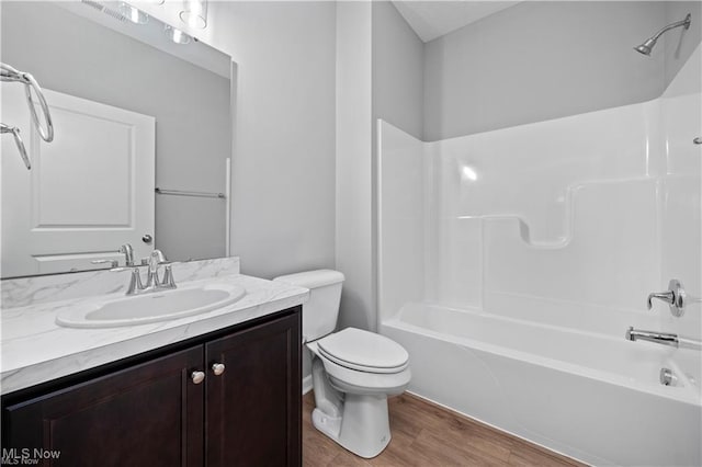full bath with vanity, toilet, wood finished floors, and  shower combination
