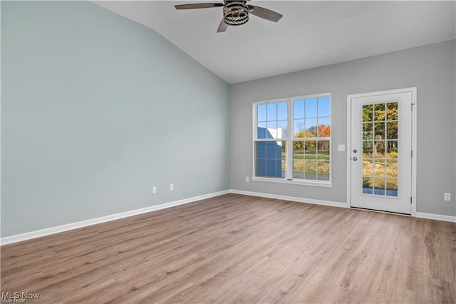 unfurnished room with baseboards, a ceiling fan, wood finished floors, and vaulted ceiling