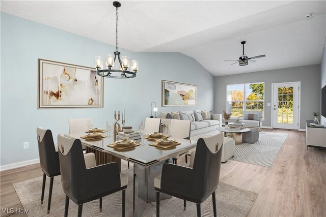 dining area with baseboards, ceiling fan with notable chandelier, light wood-style flooring, and lofted ceiling