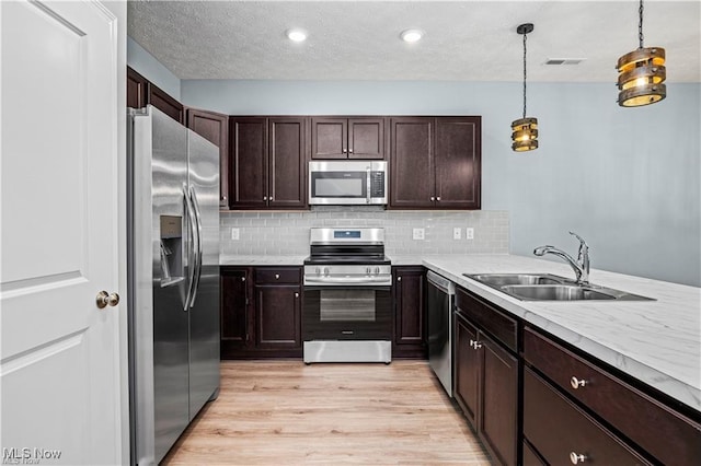 kitchen with light countertops, appliances with stainless steel finishes, a sink, and tasteful backsplash