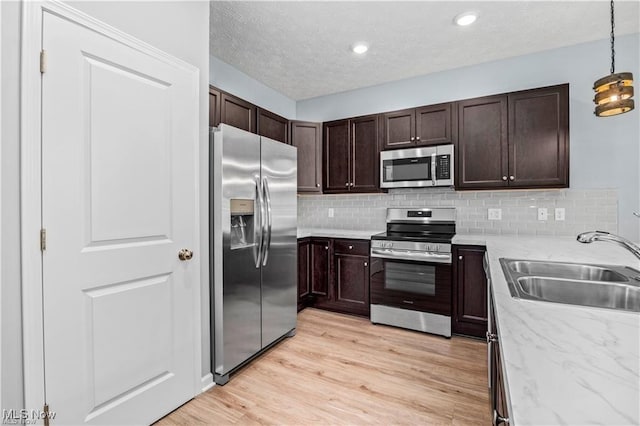 kitchen featuring a sink, appliances with stainless steel finishes, dark brown cabinets, and tasteful backsplash