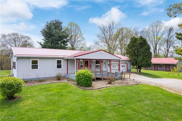 view of front of property with an attached garage, dirt driveway, a front lawn, and metal roof
