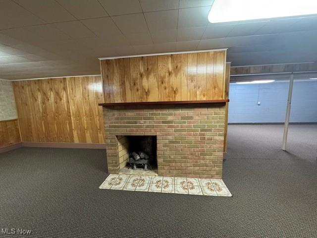 unfurnished living room featuring carpet flooring, wooden walls, and a fireplace