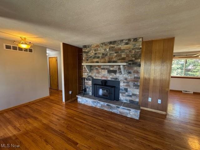 unfurnished living room featuring visible vents, baseboards, a textured ceiling, and wood finished floors