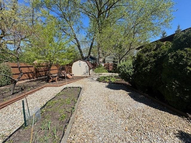 view of yard featuring an outdoor structure, a fenced backyard, and a shed
