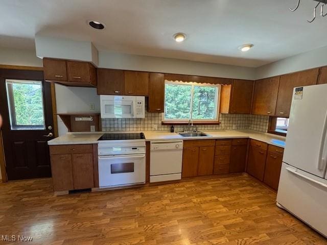 kitchen with a sink, light countertops, light wood-type flooring, and white appliances