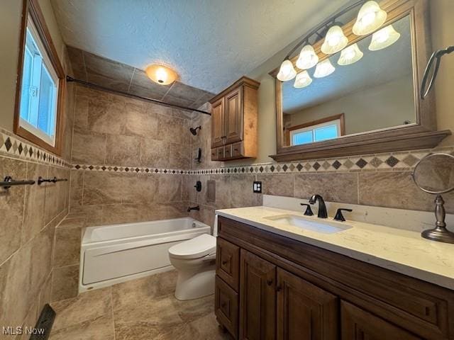 bathroom with toilet, tile walls, shower / tub combination, and vanity